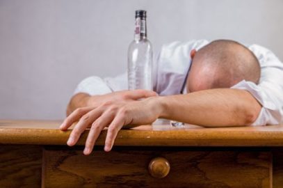 Pijany mężczyzna śpiący obok butelki wódki