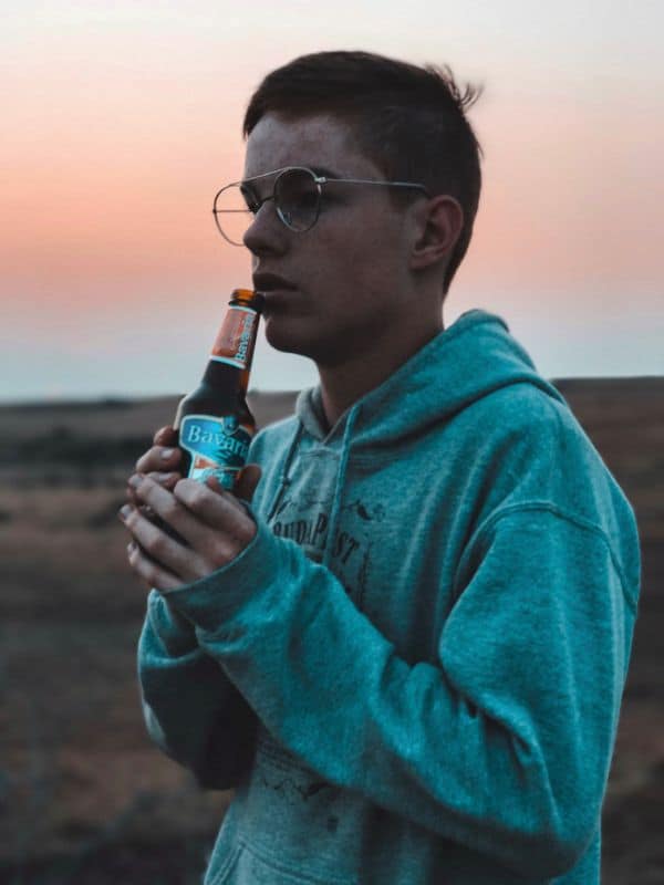 Nastolatek trzyma butelkę alkoholu